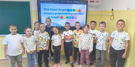Powiększ grafikę: uczniowie stoją i trzymają prace plastyczne stworzone z kropek