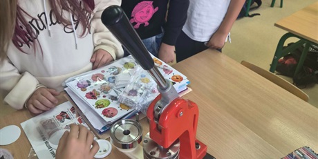 Powiększ grafikę: uczniowie stoją i trzymają prace plastyczne stworzone z kropek