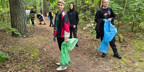 Powiększ grafikę: uczniowie chodza z workiem na smieci i w rękawiczkach zbierają śmieci